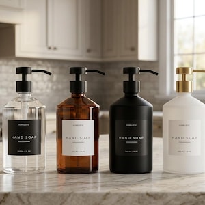 May include: Four cylindrical hand soap dispensers with pump tops. The first is clear glass with a black label, the second is amber glass with a white label, the third is matte black with a black label, and the fourth is frosted white with a white label.