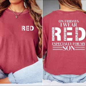 May include: A maroon t-shirt with the word "RED" printed in white. The back of the shirt has the text "ON FRIDAYS I WEAR RED. REMEMBER EVERYONE DEPLOYED ESPECIALLY FOR MY SON."