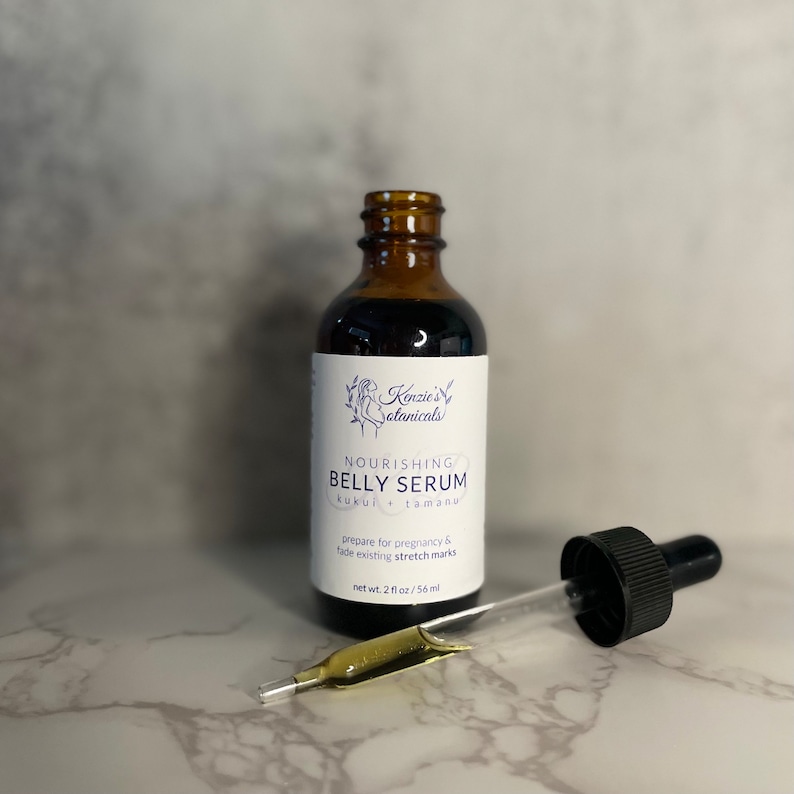 Puede incluir: Una botella de vidrio marr&oacute;n con un gotero, etiquetada como "Nourishing Belly Serum Kukui + Tamanu". La etiqueta tambi&eacute;n dice "prepare for pregnancy & fade existing stretch marks" y "net wt. 2 fl oz/56 ml".