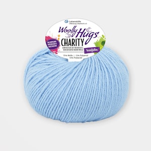 Może przedstawiać: Kulka jasnoniebieskiej przędzy z etykietą z napisem "Woolly Hugs Charity" i tekstem "75% Wolle | 15% Polyamid | 10% Polylactid".