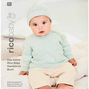 May include: A baby wearing a light blue knitted sweater with a pocket and a matching light blue knitted hat. The baby is sitting on a white surface. The text "ricobaby" is printed in black on a white background.