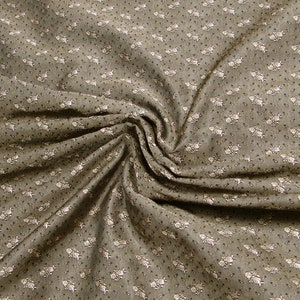 Puede incluir: Primer plano de una tela marrón con un pequeño estampado floral blanco. La tela está arrugada y tiene una textura suave.