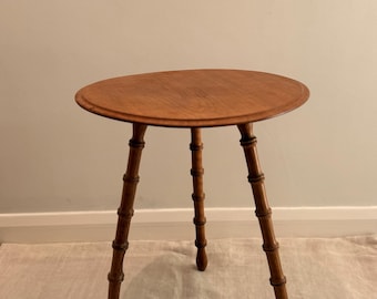 Mesa auxiliar de madera de tres patas estilo bambú, de estilo artesanal.