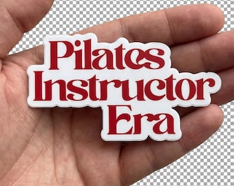 Può includere: Un adesivo bianco con testo rosso che recita "Pilates Instructor Era". L'adesivo è tenuto in una mano su uno sfondo trasparente. Il testo è in un carattere in grassetto e stilizzato.