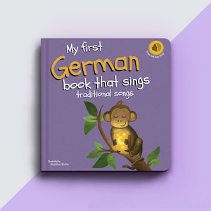 May include: Purple cover of a children's book titled "My first German book that sings traditional songs". The cover features a monkey holding a glowing light bulb and a green leafy branch.