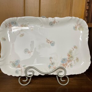 May include: A white porcelain serving platter with a scalloped edge and a floral design in shades of blue, pink, and brown.