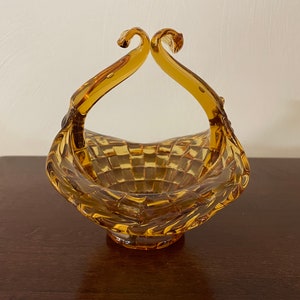 May include: Amber glass bowl with a woven pattern and two handles. The bowl is shaped like a basket.