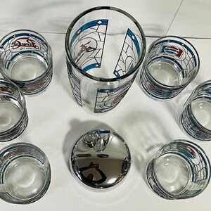 May include: A set of clear glass Pepsi-branded drinking glasses and a chrome-finished bottle stopper. The glasses feature a stained-glass design with the Pepsi logo and are arranged around a tall glass and the stopper.