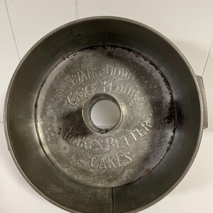 May include: Vintage metal cake pan with a raised inscription that reads "Swan Down Cake Flour Makes Better Cakes".