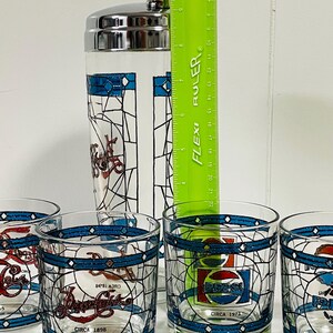 May include: A vintage Pepsi-Cola cocktail shaker and glasses set. The clear glass shaker has a silver lid and a stained-glass design. The glasses feature the Pepsi logo and the text "CIRCA 1898" and "CIRCA 1973". The ruler shows the shaker is approximately 8 inches tall.