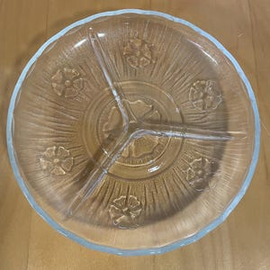 May include: A clear glass divided serving dish with a scalloped edge and a floral design. The dish has three sections.