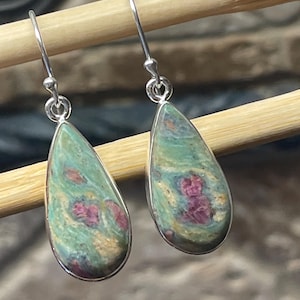 May include: A pair of silver dangle earrings featuring teardrop-shaped green and pink ruby zoisite gemstones.