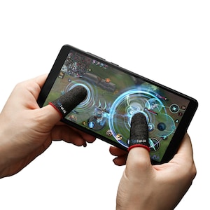 Puede incluir: Dos protectores de dedos negros con ribete rojo se usan en los dedos índices de dos manos que sostienen un teléfono inteligente. La pantalla del teléfono muestra un juego móvil con gráficos azules y blancos.