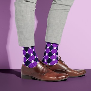 May include: A pair of brown leather shoes with purple and black diamond patterned socks. The shoes are on a purple background.