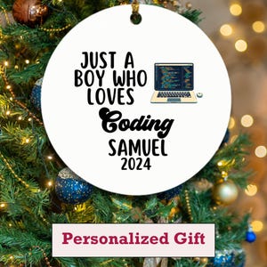 Puede incluir: Adorno navideño redondo blanco con el texto "JUST A BOY WHO LOVES Coding SAMUEL 2024" y un gráfico de portátil. El adorno tiene un agujero en la parte superior para colgarlo. La parte inferior de la imagen contiene el texto "Personalized Gift".
