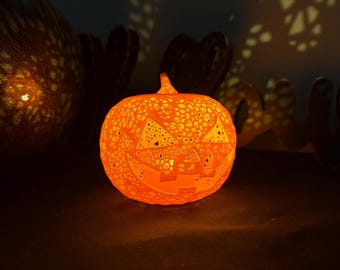 May include: An illuminated orange ceramic pumpkin with a carved face and intricate patterns. The Halloween decoration glows from within, casting shadows. A festive, seasonal item for home decor.