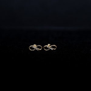 May include: A pair of gold infinity earrings with small clear stones.