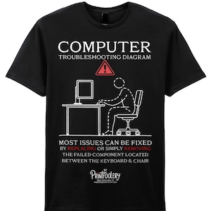 May include: Black t-shirt with a white graphic that reads "COMPUTER TROUBLESHOOTING DIAGRAM." The graphic depicts a stick figure at a desk with a computer, and the text below says, "MOST ISSUES CAN BE FIXED BY REPLACING OR SIMPLY REMOVING THE FAILED COMPONENT LOCATED BETWEEN THE KEYBOARD & CHAIR."