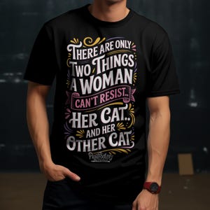 A man wearing a black t-shirt with a colourful cat design and a red wristwatch.