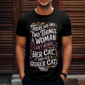 A man wearing a black short-sleeved t-shirt with cat lover text graphic against a wooden slat background.
