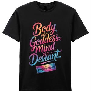 Può includere: T-shirt nera con la scritta multicolore "Body of a Goddess, Mind of a Deviant". È presente anche un piccolo logo rettangolare con la scritta "Printfelory etsy.com".