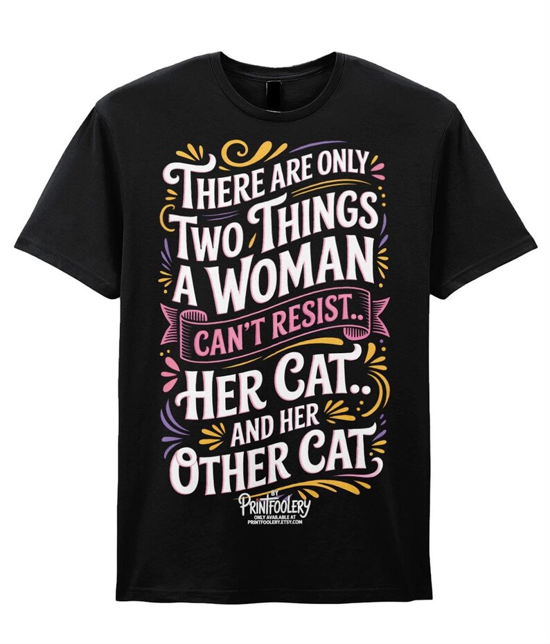 A black t-shirt featuring colourful graphic text that reads There are only two things a woman can't resist.. her cat.. and her other cat.