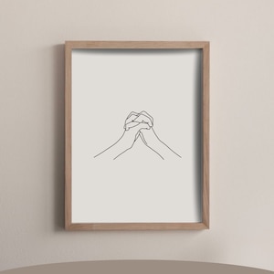May include: A black and white line drawing of two hands clasped together. The drawing is framed in a light wood frame and is hanging on a light beige wall. The text "A4 & A3" is printed below the frame, along with the dimensions "21 x 29.7 cm | 29.7 x 42 cm".