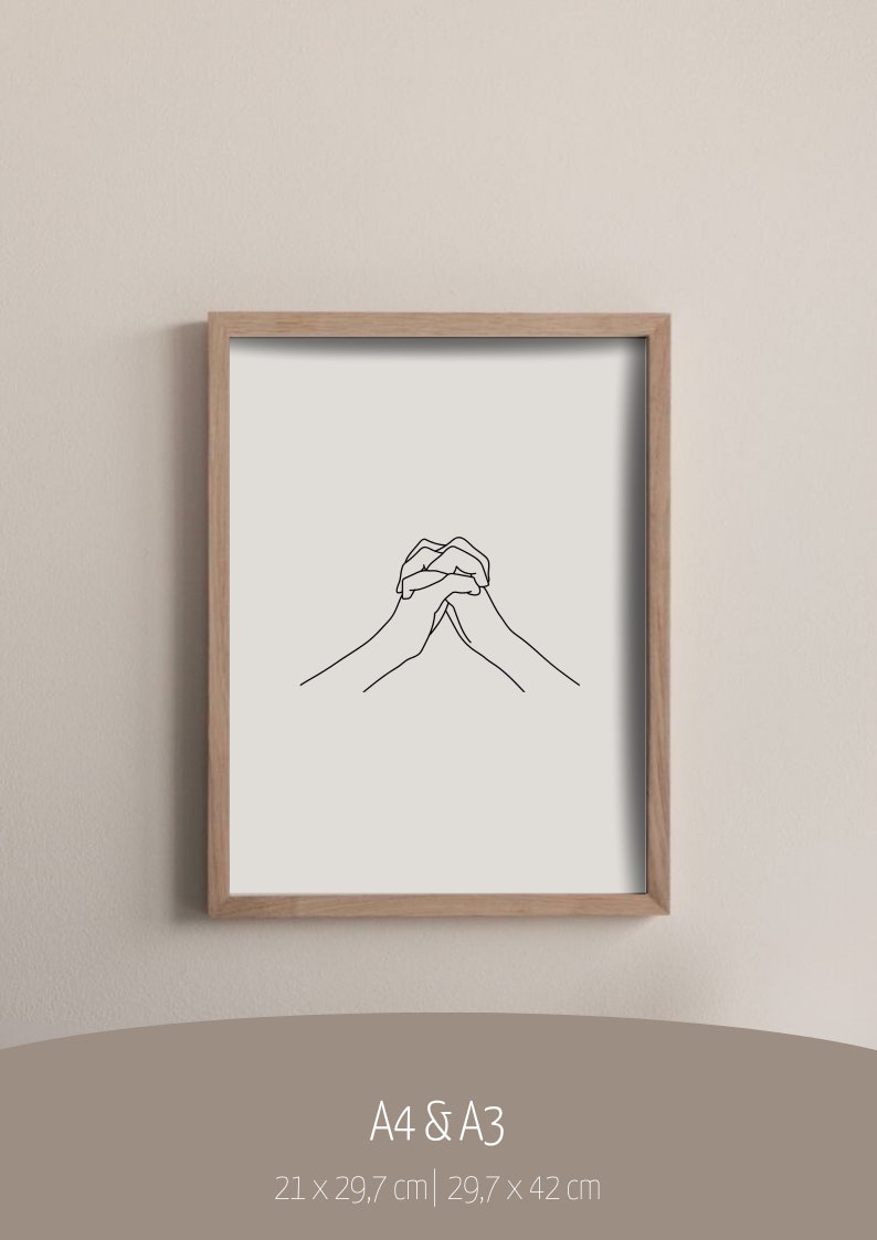 May include: A black and white line drawing of two hands clasped together. The drawing is framed in a light wood frame and is hanging on a light beige wall. The text "A4 & A3" is printed below the frame, along with the dimensions "21 x 29.7 cm | 29.7 x 42 cm".