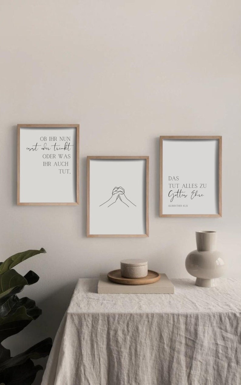 May include: Three framed prints with minimalist designs. The top print features a quote in German, the middle print shows a simple line drawing of two hands clasped together, and the bottom print features a quote in German with the text "DAS TUT ALLES ZU Gottes Ehre 1.KORINTHER 10:31".