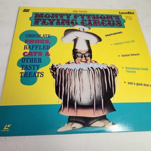 May include: A yellow and blue poster for the ninth Monty Python's Flying Circus LaserDisc. The poster features a cartoon chef holding a large pot of wriggling worms. The text on the poster reads "Chocolate Frogs, Baffled Cats & Other Tasty Treats" and "Featuring: Confuse-A-Cat, Animal Debates, Nauseating Candy Factory, and a good deal more."