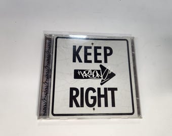 May include: A white sign with black text that reads "KEEP RIGHT" with a black arrow pointing to the right. The arrow has the word "KRION" written on it.