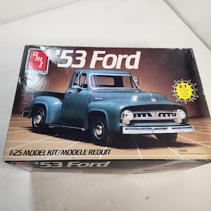 May include: A model kit box featuring a teal '53 Ford pickup truck. The box has the text "'53 Ford" and "1:25 Model Kit". The box has a brown background with a yellow burst that says "3-1".
