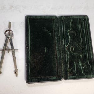 May include: A vintage compass with a green velvet case. The compass has a silver finish and is in good condition.