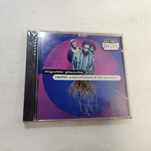 May include: Sealed CD of Digable Planets' album "Reachin' (A New Refutation of Time and Space)". The cover features a group photo of the band members against a purple and blue background with a root-like graphic. A sale price tag is visible.