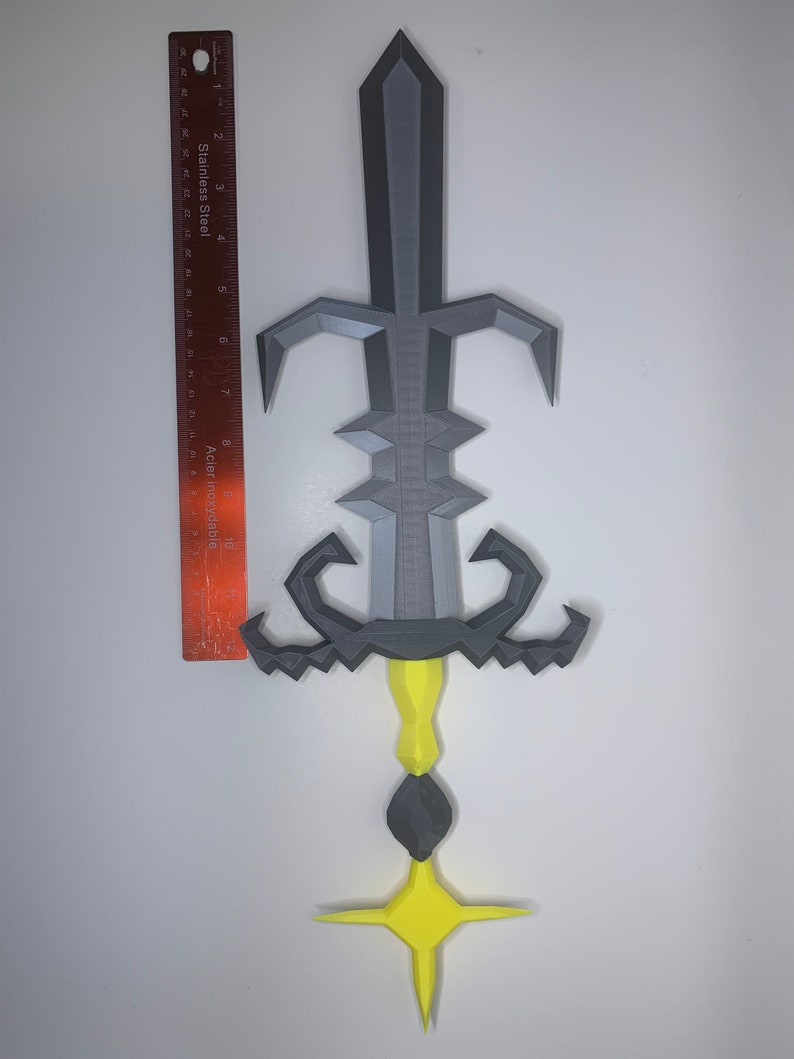 May include: A gray and yellow 3D printed sword with a star-shaped base. The sword has a detailed design with a pointed tip and a curved handle.