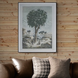 May include: A framed black and white print of a palm tree in a desert landscape. The print is hanging on a wood panel wall.