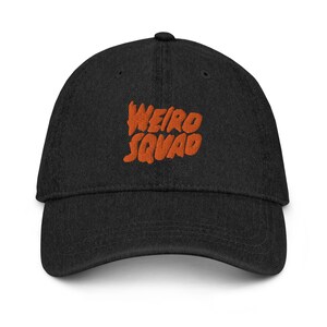 Puede incluir: Una gorra de béisbol de denim negro con un logotipo bordado en naranja que dice "Weird Squad".