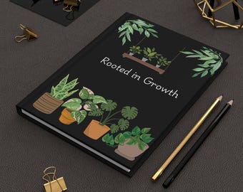 Può includere: Un diario nero con la scritta "Rooted in Growth" e illustrazioni di piante in vaso. La copertina presenta varie piante verdi in vasi marroni e arancioni. Sono visibili anche matite dorate e nere e fermagli dorati.