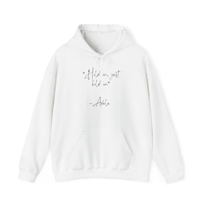 May include: White hoodie with a front pocket and drawstring hood. The front of the hoodie features the quote "Hold on, just hold on" followed by the name "Adele" in a handwritten style font.