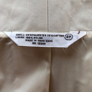 May include: A white tag with black text that reads "SHELL: 65% POLYESTER 35% COTTON (8P LINING: 100% NYLON MADE IN HONG KONG RN 15099"