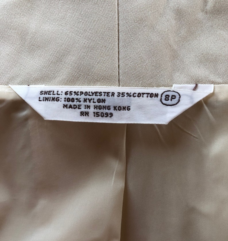 May include: A white tag with black text that reads "SHELL: 65% POLYESTER 35% COTTON (8P LINING: 100% NYLON MADE IN HONG KONG RN 15099"
