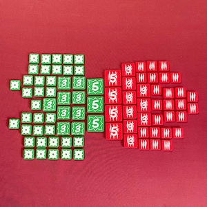 May include: A collection of green and red game pieces with numbers 3 and 5 printed on them. The green pieces are arranged in a rectangular shape, while the red pieces are arranged in a triangular shape.