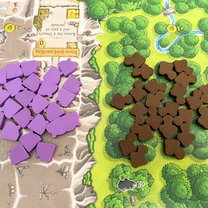 May include: A game board with purple and brown game pieces. The board has a green and brown background with a river and trees. The text on the board reads "Entry-level dwelling 0 Room for 2 Dwarfs and 1 pair of animals."