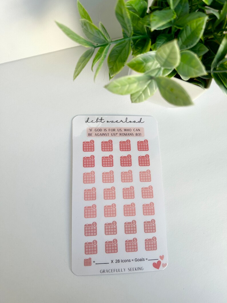 May include: A sheet of 28 pink and peach calendar stickers with a dollar sign on each. The text "debt overload" is at the top of the sheet. The text "IF GOD IS FOR US, WHO CAN BE AGAINST US? ROMANS 8:31" is in a smaller font below the title. The text "X 28 Icons = Goals" is at the bottom of the sheet. The text "GRACEFULLY SEEKING" is below the equation. Two pink hearts are at the bottom right corner of the sheet.