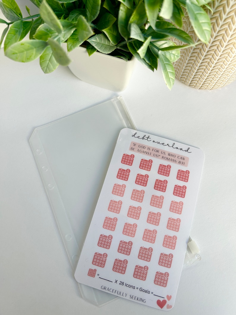 May include: A sheet of stickers with 28 calendar icons, each with a dollar sign inside. The stickers are in shades of pink and red. The text "debt overload" is at the top of the sheet. The text "IF GOD IS FOR US, WHO CAN BE AGAINST US? ROMANS 8:31" is below the icons. The text "X 28 Icons = Goals" is at the bottom of the sheet, along with the text "GRACEFULLY SEEKING".