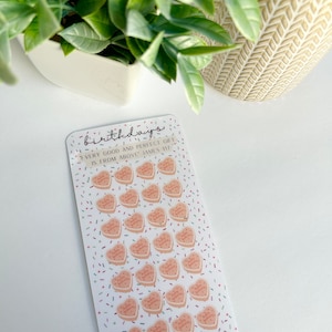 May include: A sheet of stickers with 28 pink heart-shaped stickers with the text "Happy Birthday" on each. The stickers are on a white background with confetti sprinkles. The text "Every good and perfect gift is from above James 1:17" is at the top of the sheet. The text "X/28 Icons = Goals" and "Gracefully Seeking" is at the bottom of the sheet.