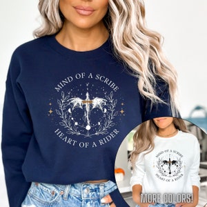 May include: A navy blue sweatshirt with a white graphic design featuring a stylized dragon with the text "Mind of a Scribe, Heart of a Rider".