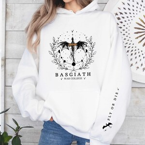 Hoodie featuring the Basgiath War College emblem, ideal for fans of dragons and fantasy books. Front design showcases the college's prestige, while the sleeve displays a dragon beside the quote Fly or Die. Perfect for Fourth Wing enthusiasts.
