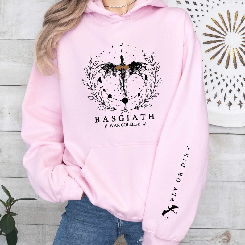 Hoodie featuring the Basgiath War College emblem, ideal for fans of dragons and fantasy books. Front design showcases the college's prestige, while the sleeve displays a dragon beside the quote Fly or Die. Perfect for Fourth Wing enthusiasts.