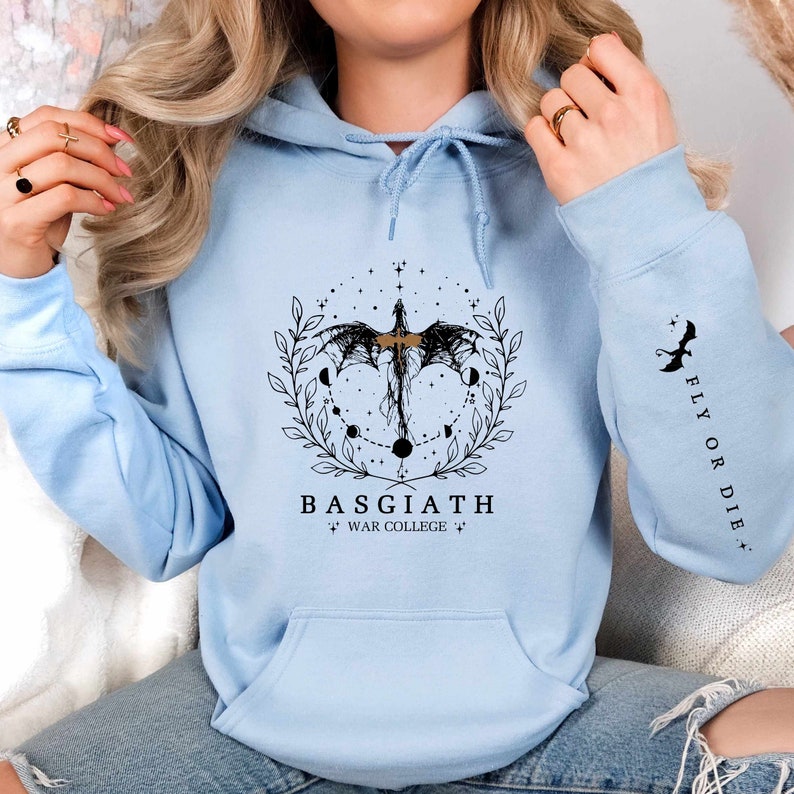 Hoodie featuring the Basgiath War College emblem, ideal for fans of dragons and fantasy books. Front design showcases the college's prestige, while the sleeve displays a dragon beside the quote Fly or Die. Perfect for Fourth Wing enthusiasts.